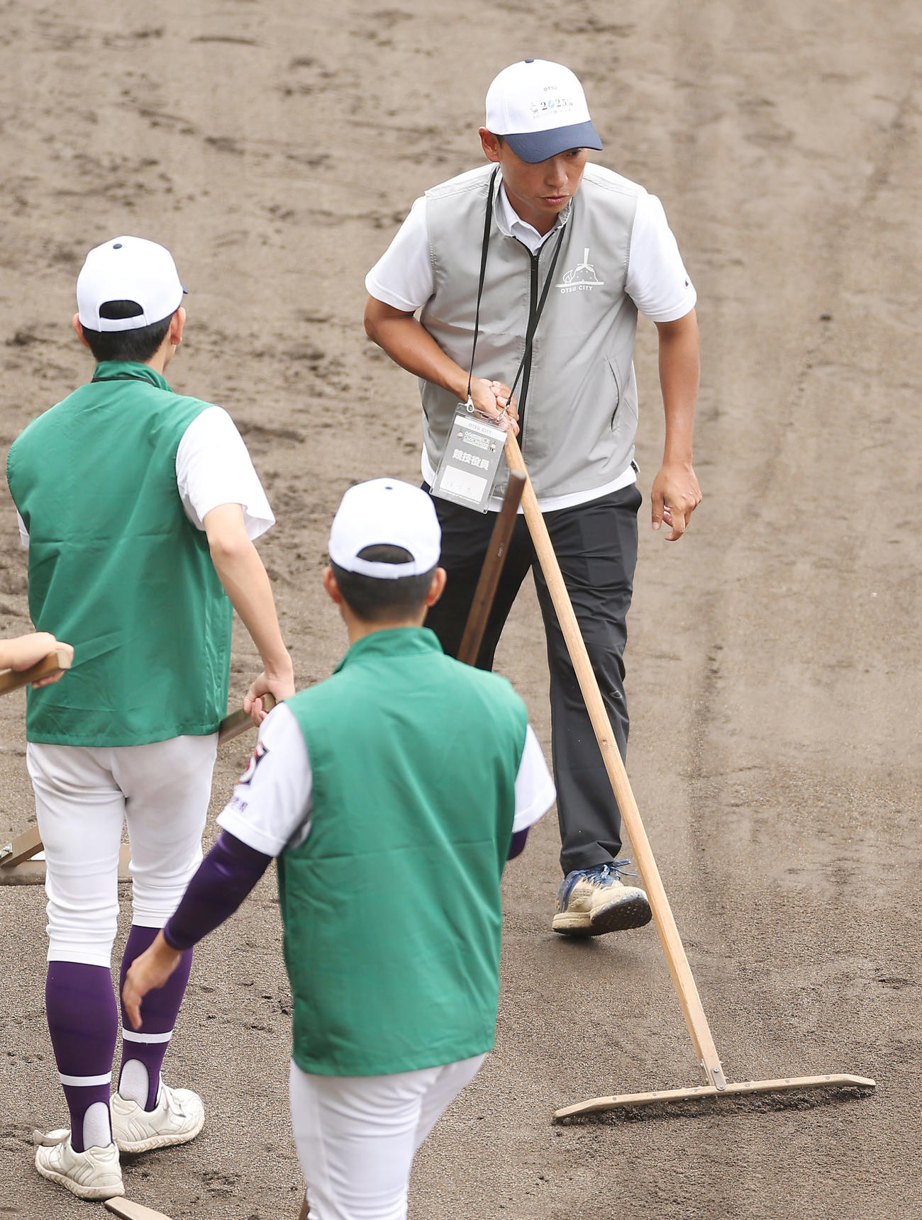 山梨学院対尽誠学園　グラウンド整備を行う滋賀短大付・保木監督（右）と選手たち（撮影・前田充）