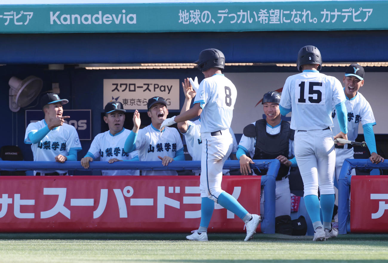 山梨学院対帝京　7回表山梨学院2死二塁、菰田の中前適時打で二塁走者石井が生還しナインの出迎えを受ける（撮影・柴田隆二）
