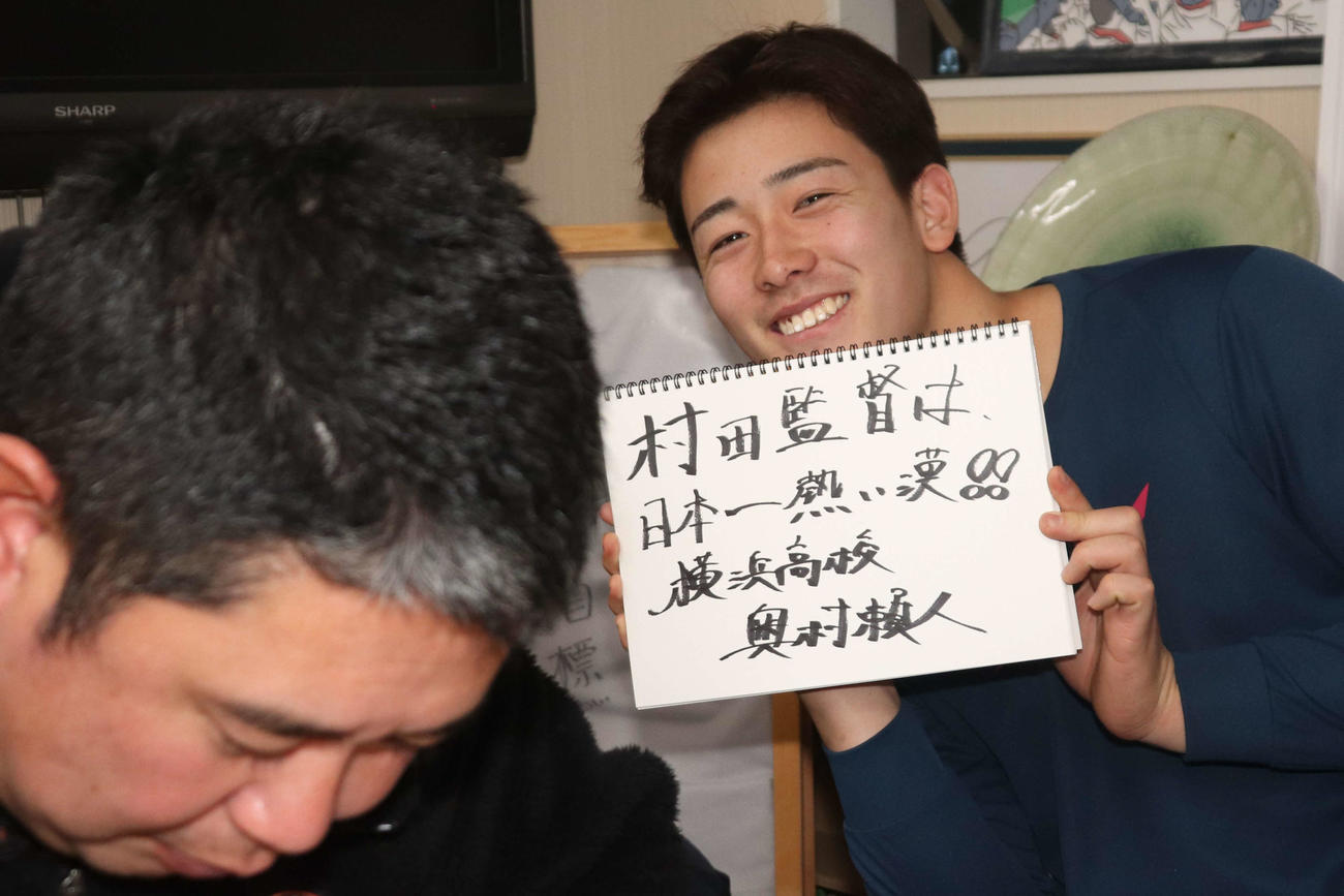 村田浩明監督へのメッセージを書き、村田監督の後ろから笑顔を見せる奧村頼（撮影・保坂淑子）