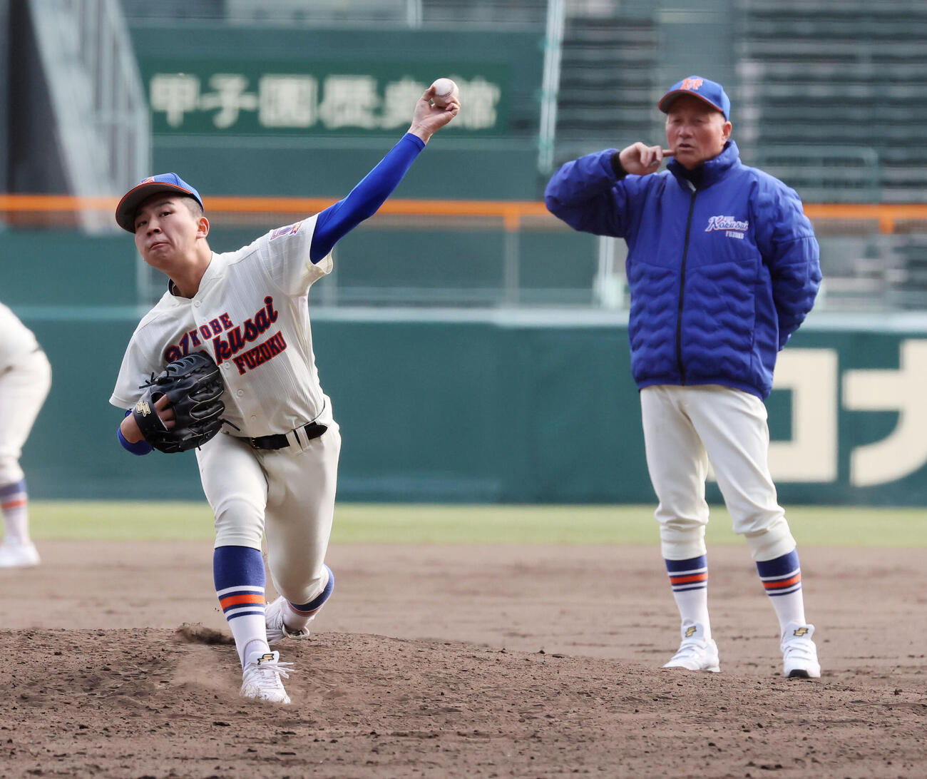マウンドで投球練習する神戸国際大付・秋田と右は青木監督（撮影・加藤哉）