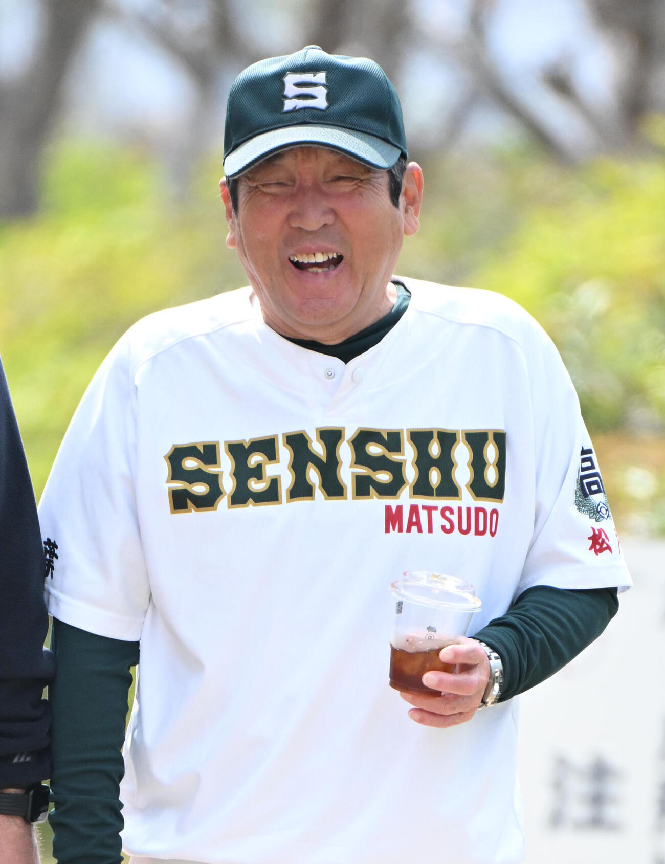 コーヒーを片手に笑顔を見せる専大松戸の持丸修一監督（撮影・石井愛子）