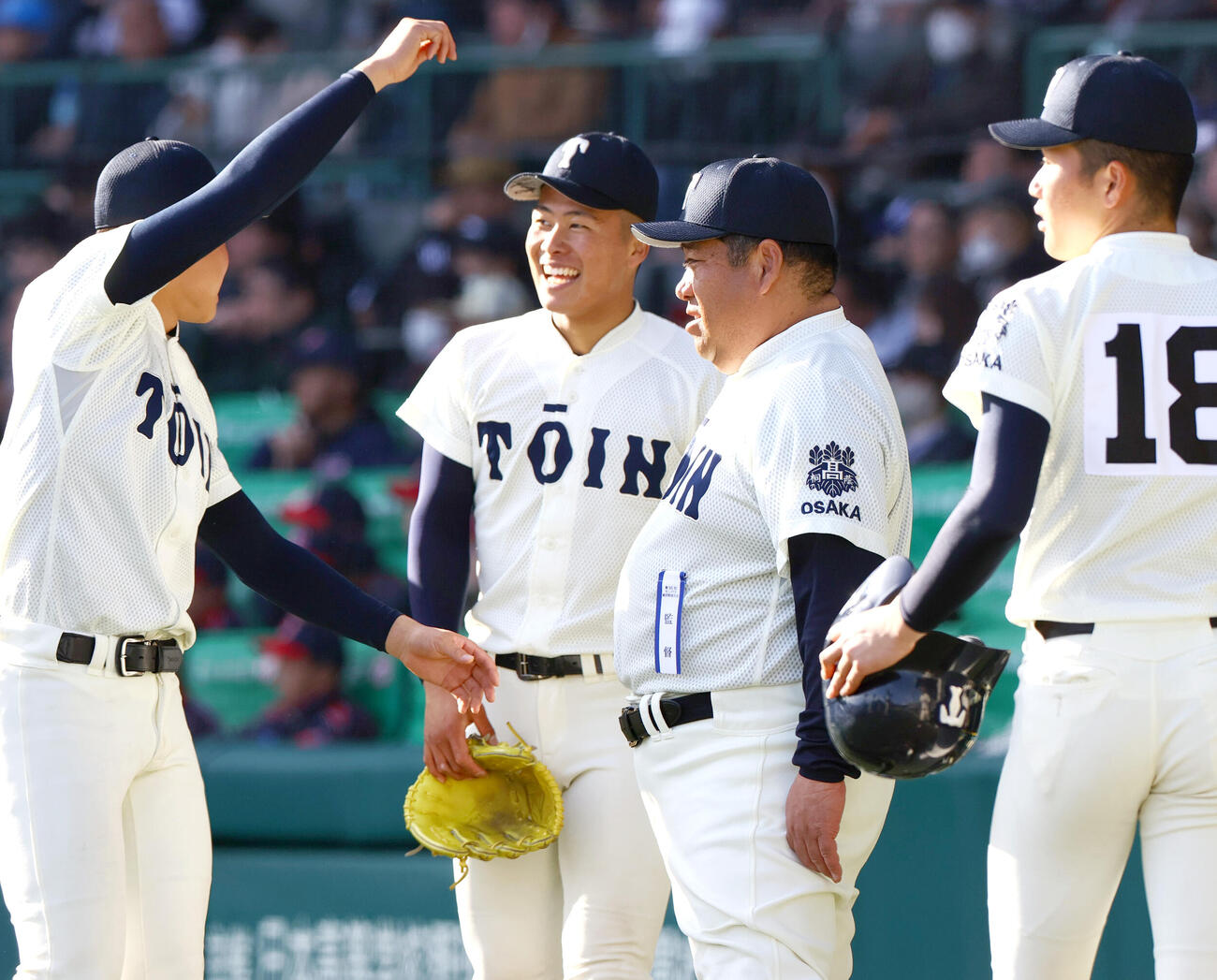 第96回選抜高校野球大会・8日目　神村学園対大阪桐蔭　8回を投げ終えた中野大虎（左から2人目）は西谷浩一監督の話しを聞きながら笑顔を見せる（2024年3月撮影）