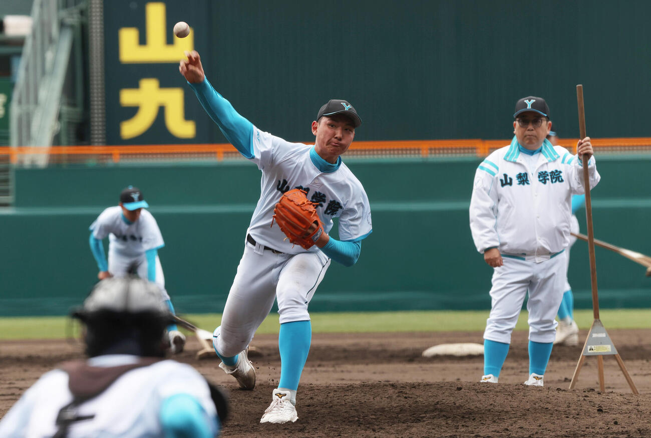 甲子園球場のマウンドで投球練習する山梨学院の菰田。右は吉田監督（撮影・上山淳一）