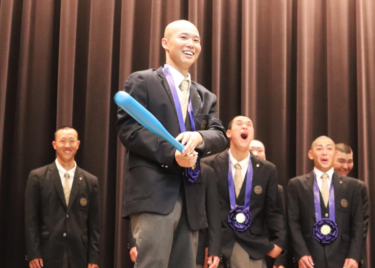 センバツ優勝報告会で吹奏楽部の演奏を背に、トスバッティングを披露する無茶振りに笑顔で応じた、大阪桐蔭・主将の黒川（撮影・中島麗）
