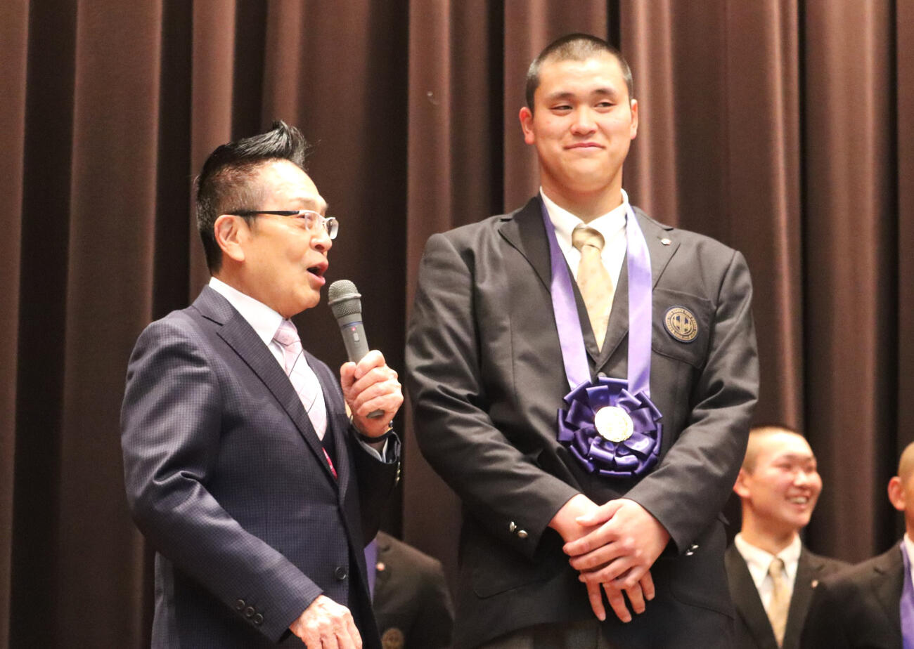 センバツ優勝報告会で大阪桐蔭吹奏楽部の梅田隆司総監督から壇上で声をかけられ、笑みを浮かべる川本（撮影・中島麗）