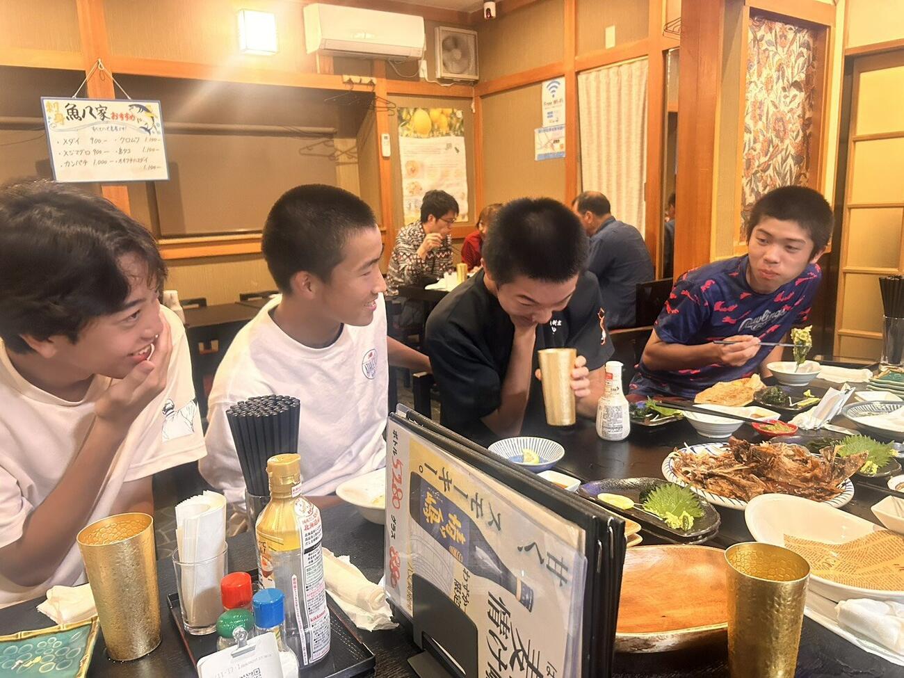 大皿にのった魚を食べる八丈の選手たち（撮影・平山連）