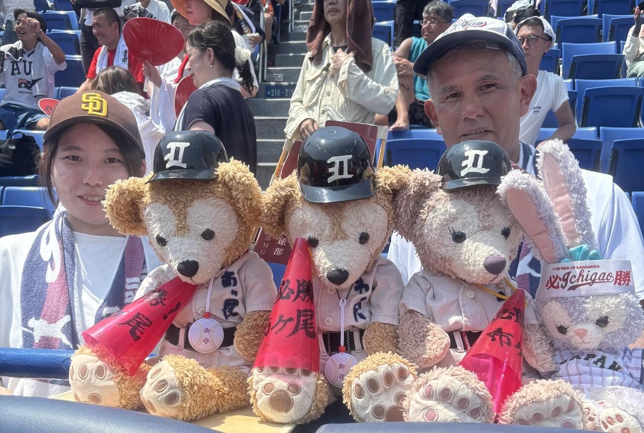 市ケ尾スタンドのユニホームを着たダッフィー人形と、同校元マネージャーの小山未歩さん（左）、祖父の一樹さん（撮影・服部航大）
