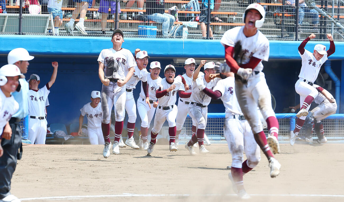 明秀学園日立対常総学院　タイブレークの延長10回裏、サヨナラ勝ちし喜ぶ常総学院の選手たち。後方左は万歳する島田直也監督（撮影・野上伸悟）