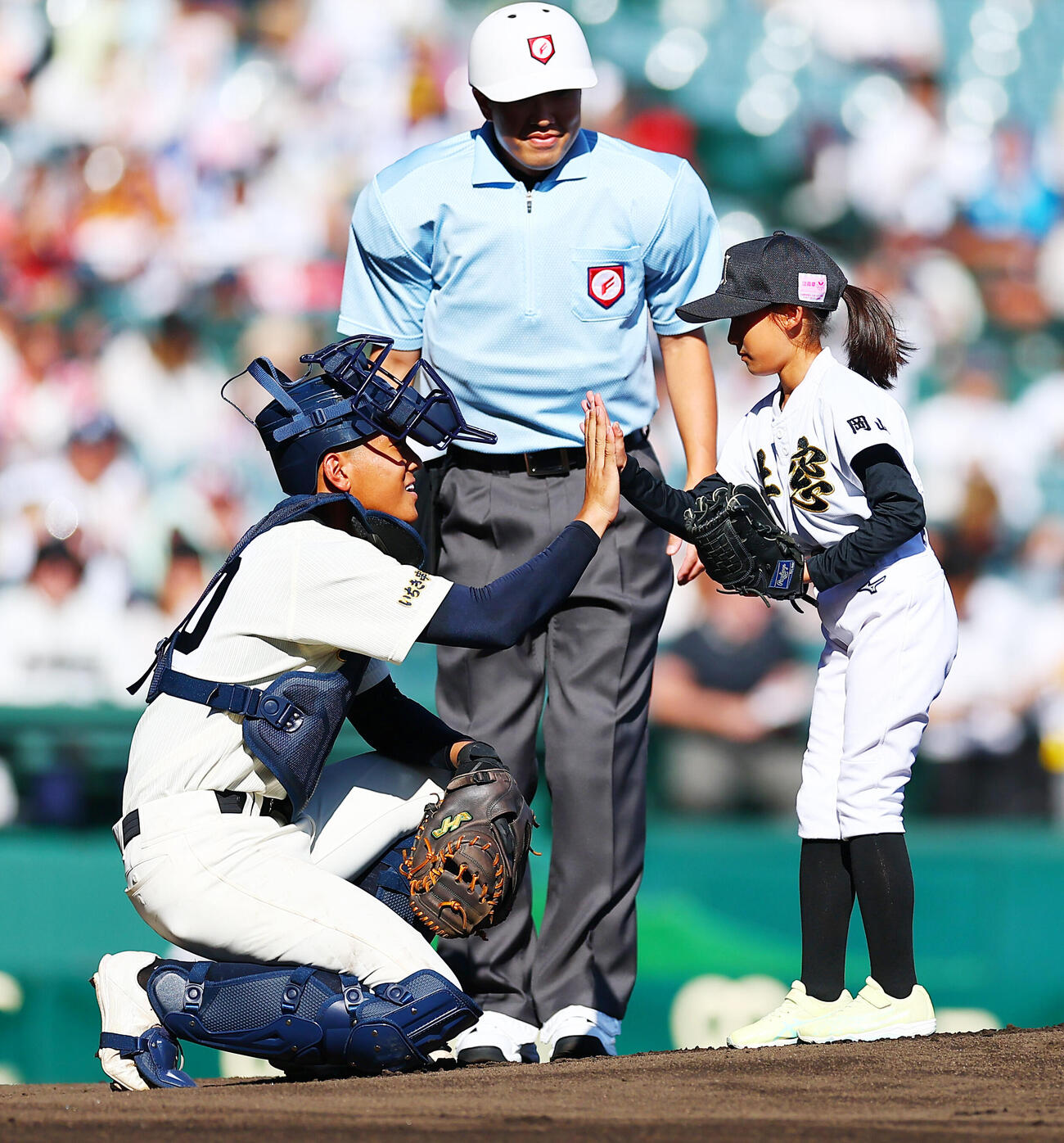 東筑対神村学園　始球式を行った岡山・瀬戸内市立牛窓東小の服部和果さん（右）とタッチする神村学園・川本羚豪（撮影・野上伸悟）
