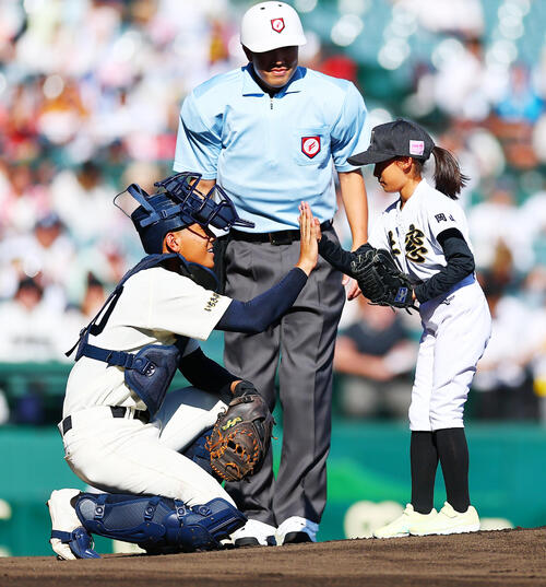 東筑対神村学園　始球式を行った岡山・瀬戸内市立牛窓東小の服部和果さん（右）とタッチする神村学園・川本羚豪（撮影・野上伸悟）