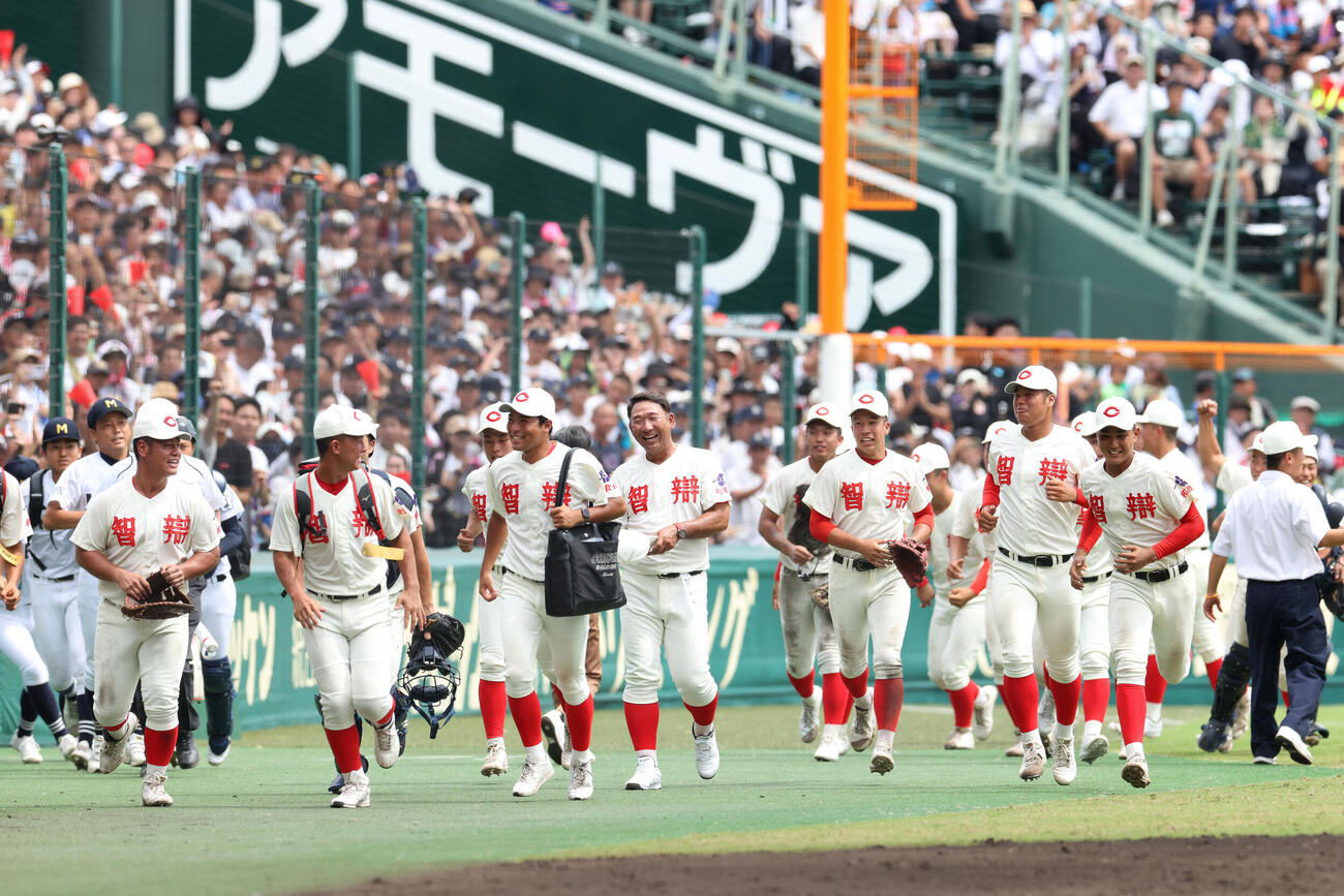 智弁和歌山対敦賀気比　延長戦の末、敦賀気比に勝利し、選手たちと笑顔で引き揚げる智弁和歌山・中谷仁監督（中央）（撮影・河田真司）