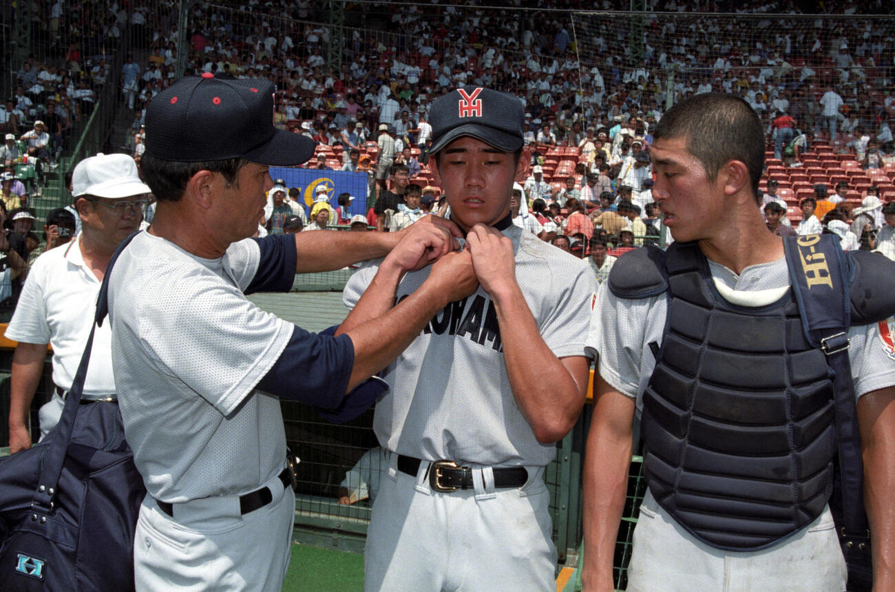 98年8月、調子の戻らない松坂大輔（中央）は渡辺元智監督（左）からユニホームのボタンをとめてもらう