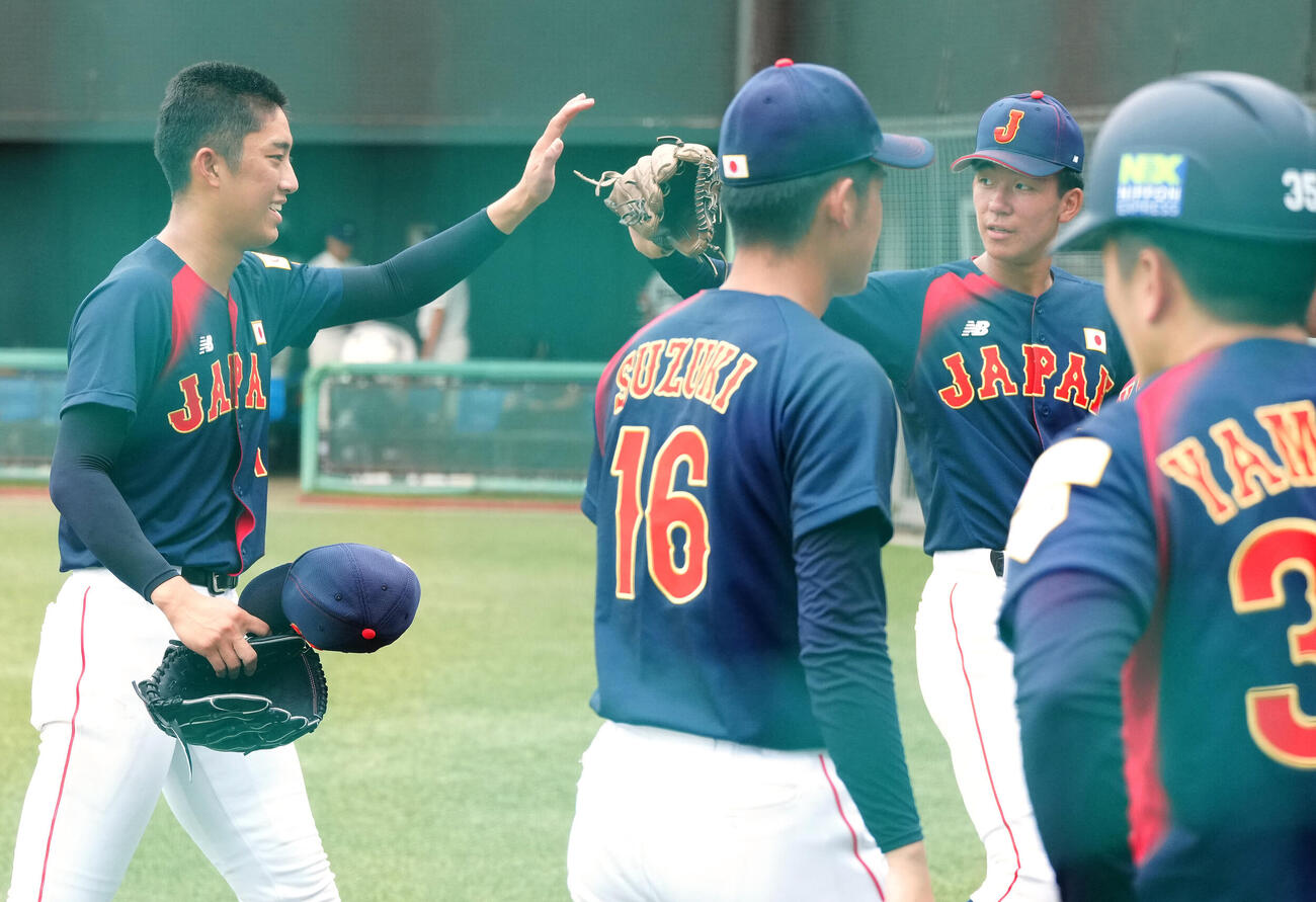高校日本代表対明大　2回裏終了後、高校日本代表・萬谷堅心（後方右）とタッチを交わす先発の織田翔希（撮影・江口和貴）