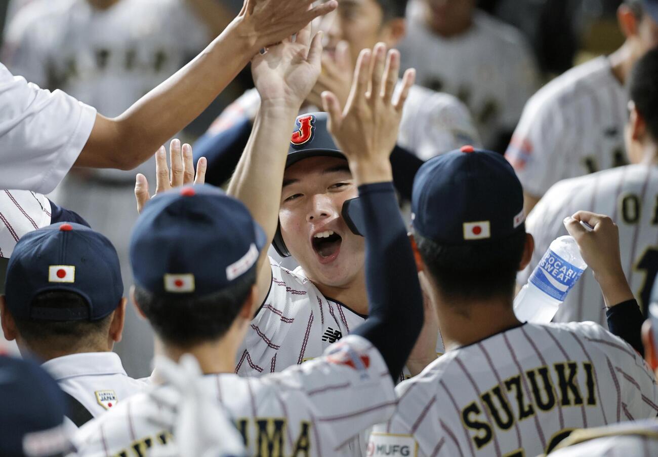台湾戦の1回、萬谷の適時打で生還し、ナインに迎えられる山田（共同）