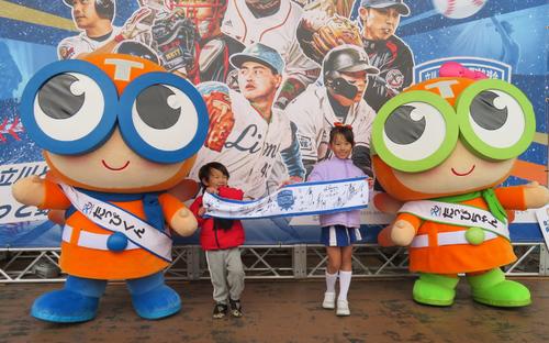 立飛グループ公式イメージキャラクター「たっぴくん・たっぴちゃん」と名球会メンバーサイン入りタオルを手にする後藤由宇さん(左)と後藤由依さん(右)