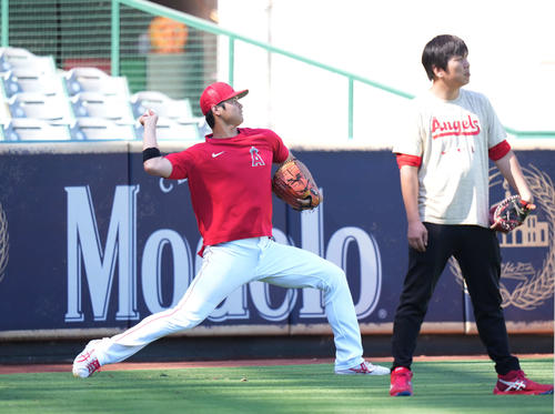 試合前、野手が放った打撃練習のボールを見張る一平さん（右）に付き添われキャッチボールする翔平さん（撮影・菅敏）
