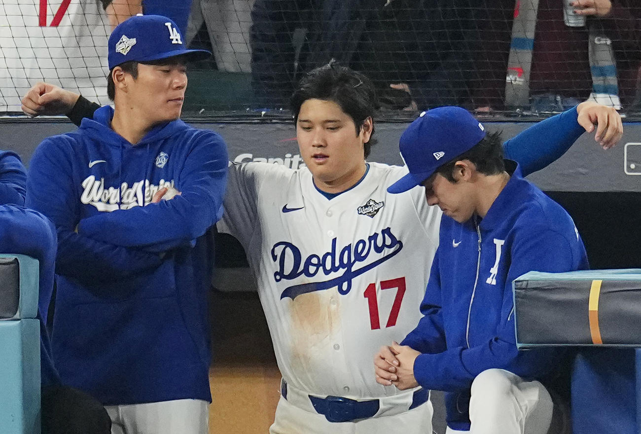 10月27日、ワールドシリーズ第3戦、ドジャース対ブルージェイズ　12回、ベンチで試合を見守る山本（左）と佐々木（右）の間に入り、肩を組んで話す大谷（撮影・菅敏）