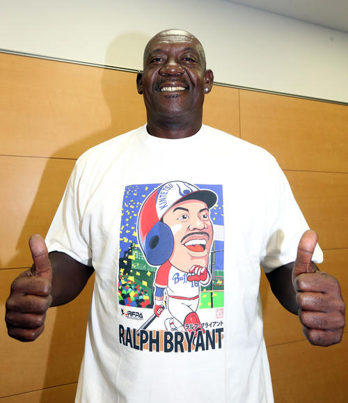 インタビュー後、現役時代の自身が描かれたイラストTシャツを着てサムアップするブライアント氏（撮影・狩俣裕三）