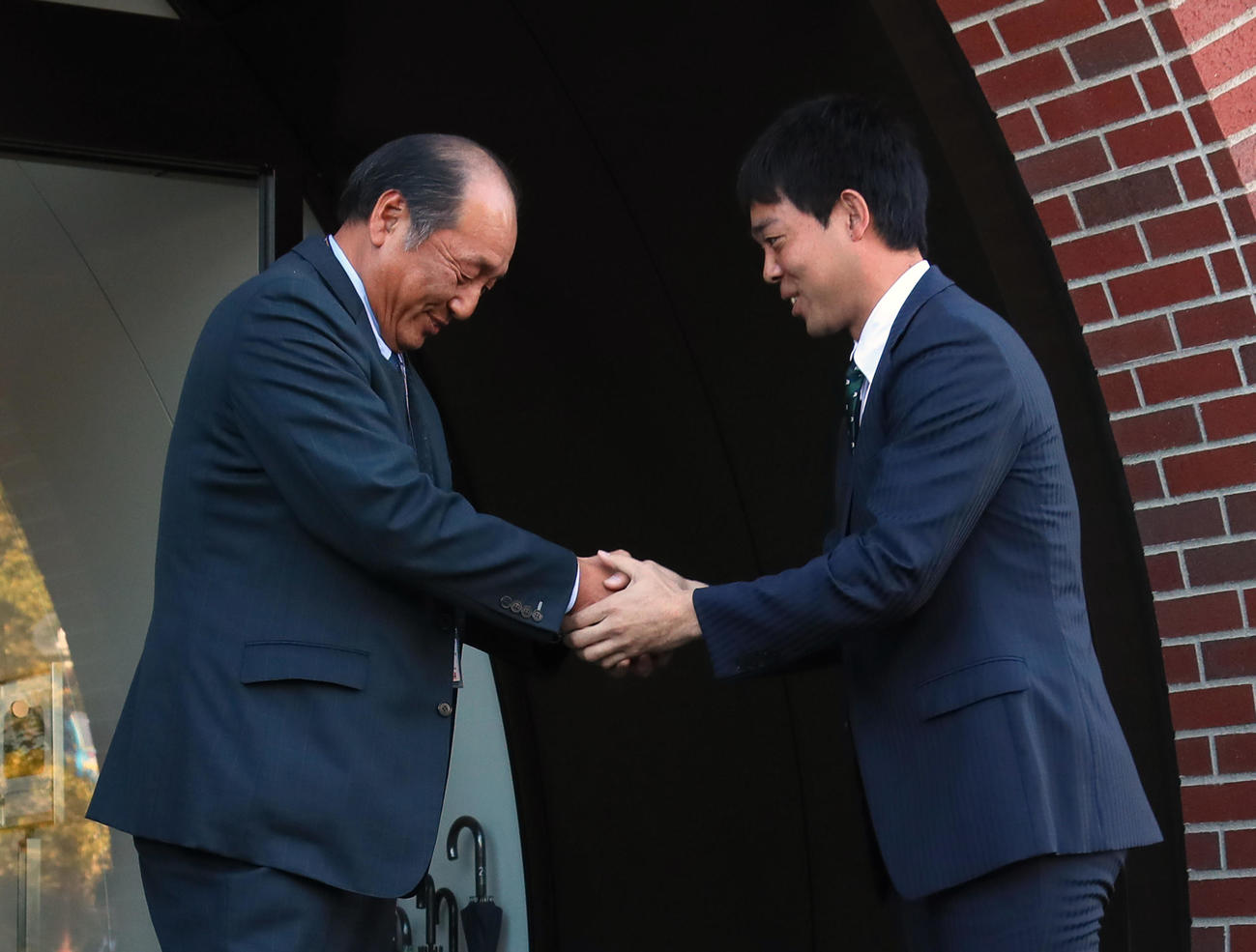 レッズ秋山（右）は西武の事務所にあいさつに訪れ渡辺GMに握手で迎えられる（撮影・足立雅史）