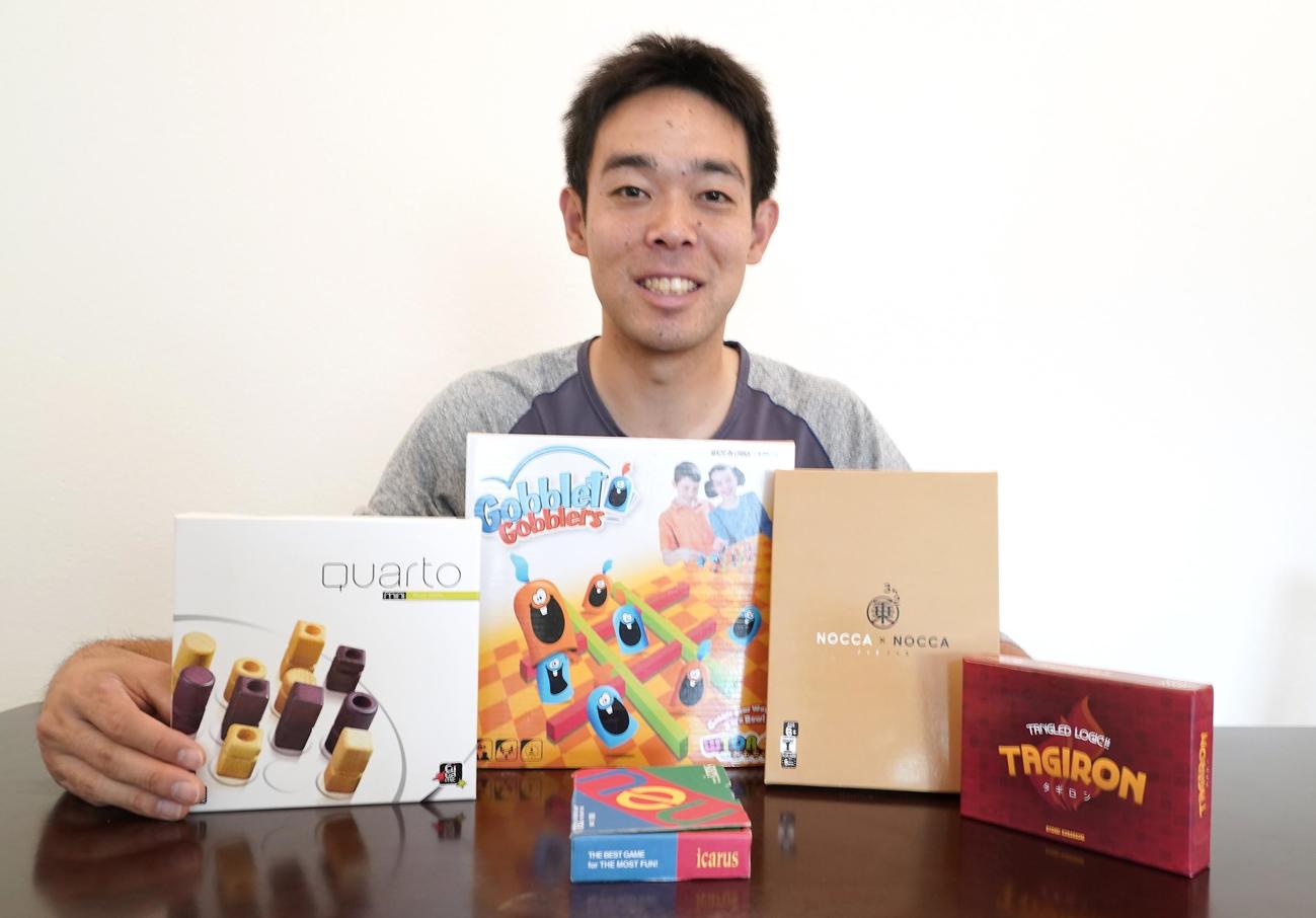 滞在先でプレーしているボードゲームとカードゲームを前に笑顔を見せるレッズ秋山（本人提供）