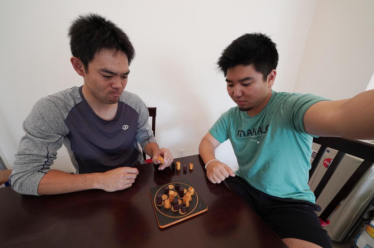 ボードゲームのクアルトで対戦するルーク篠田通訳とレッズ秋山（本人提供）