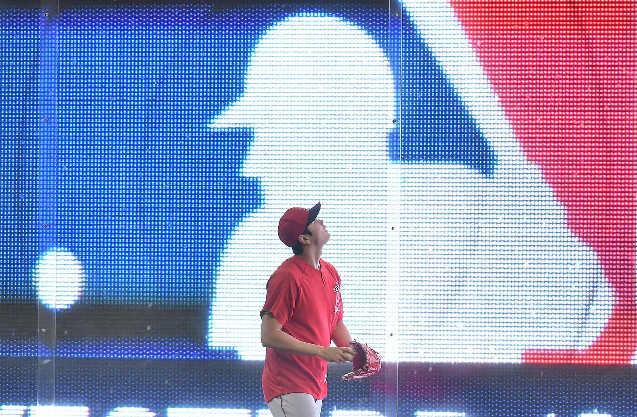 キャッチボールをするエンゼルス大谷は、外野フェンスに映し出されるMLBのロゴを見つめる（2019年6月20日撮影）
