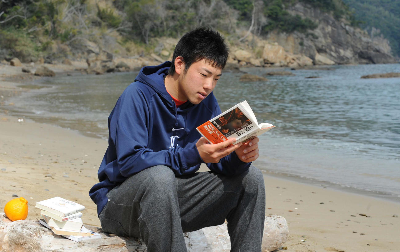 10年2月、春季キャンプの休日、海岸の流木に座り読書を楽しむ雄星