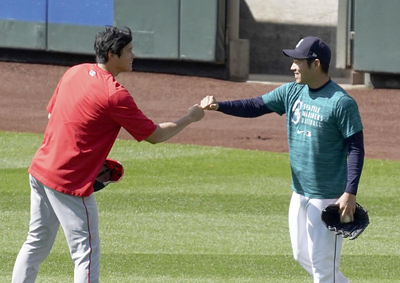 試合前の練習の合間に、マリナーズ菊池（右）とグータッチを交わすエンゼルス大谷（共同）