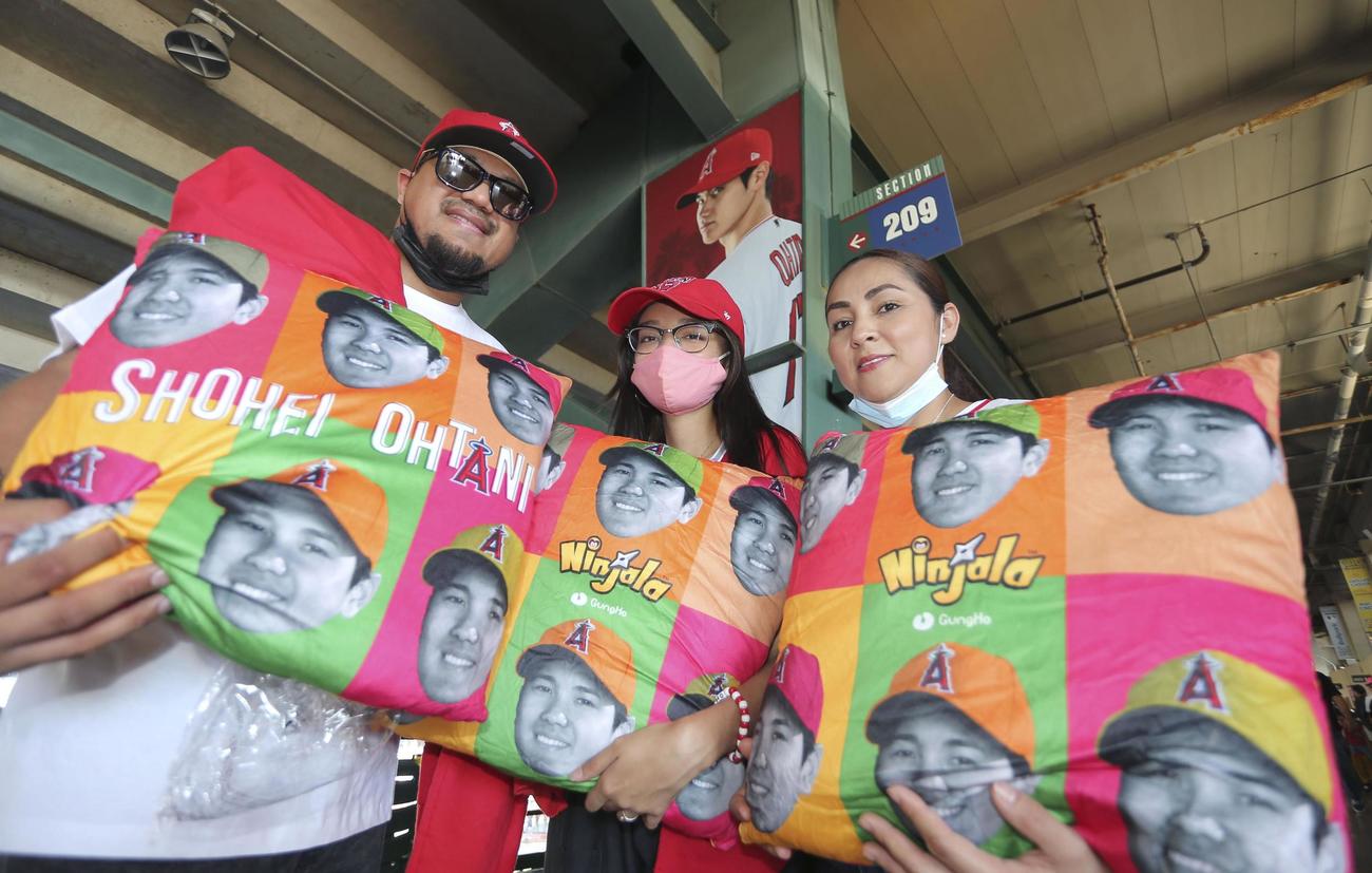 先着で配られた、エンゼルス大谷の顔がデザインされた、クッションのような大谷ピロー（枕）を手にするファン（共同）