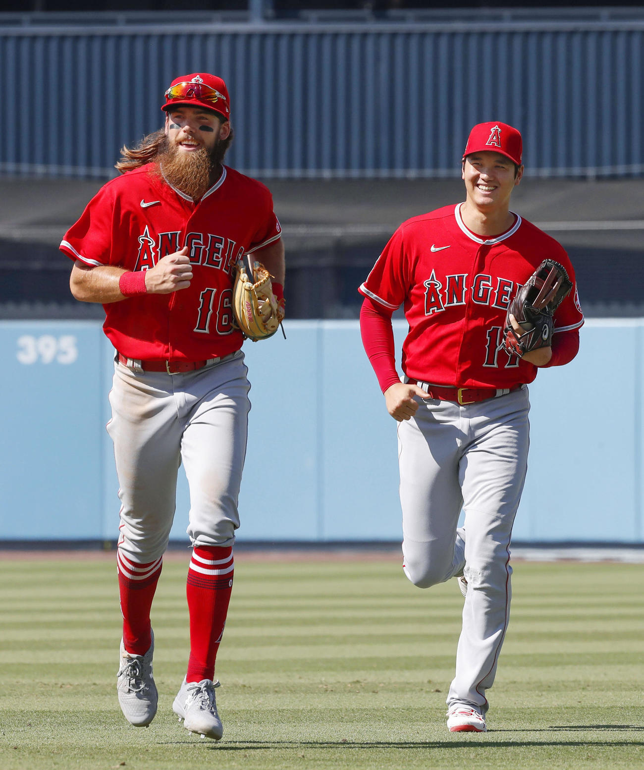 ドジャース戦の8回を終え、笑顔でベンチに戻るエンゼルスの右翼手大谷。左はマーシュ＝ロサンゼルス（共同）