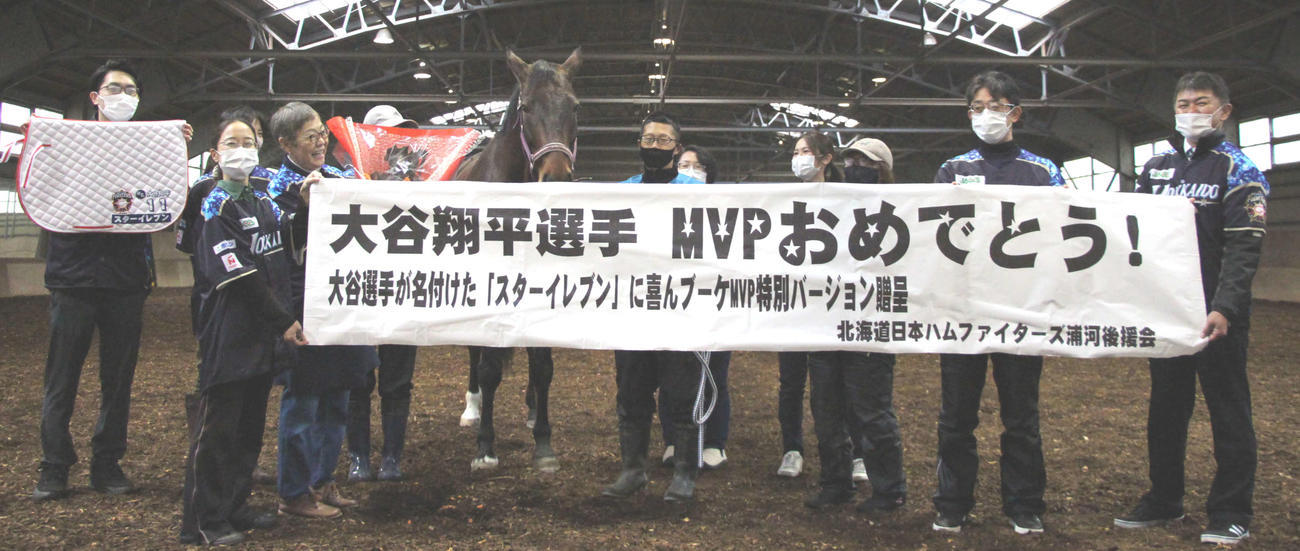 大谷のア・リーグMVP受賞を祝し、日本ハム時代の大谷に命名された乗馬療育用馬「スターイレブン」（中央左）にブーケを贈呈する関係者たち（浦河町提供）