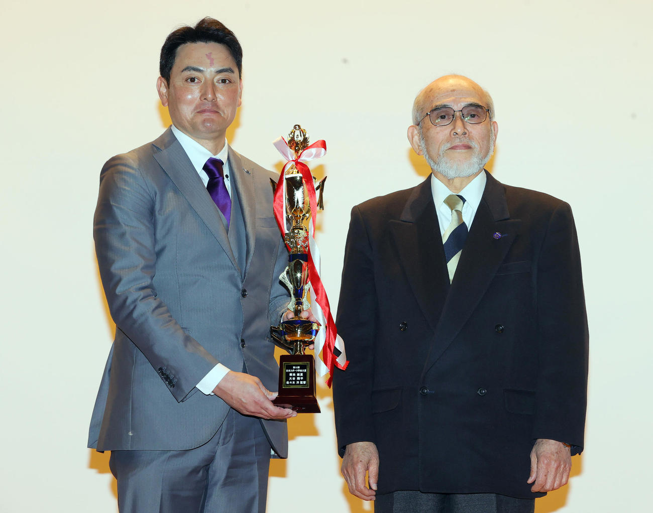 日本スポーツ学会大賞を受賞し、第1回受賞者の坂田元国士舘大教授（右）からトロフィーを授与される花巻東・佐々木監督（撮影・野上伸悟）