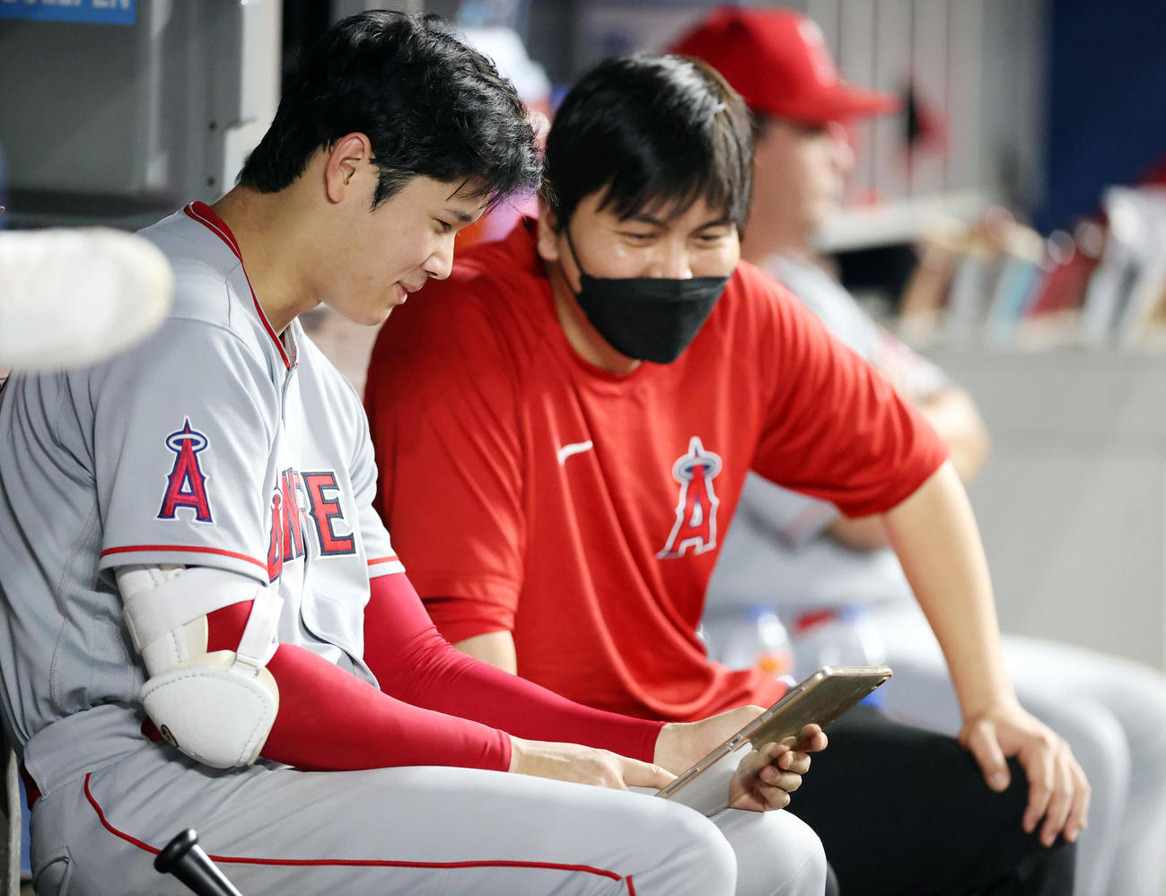 マーリンズ対エンゼルス　8回裏、ベンチでタブレットを見ながら笑顔を見せる大谷（左）と水原通訳（撮影・狩俣裕三）