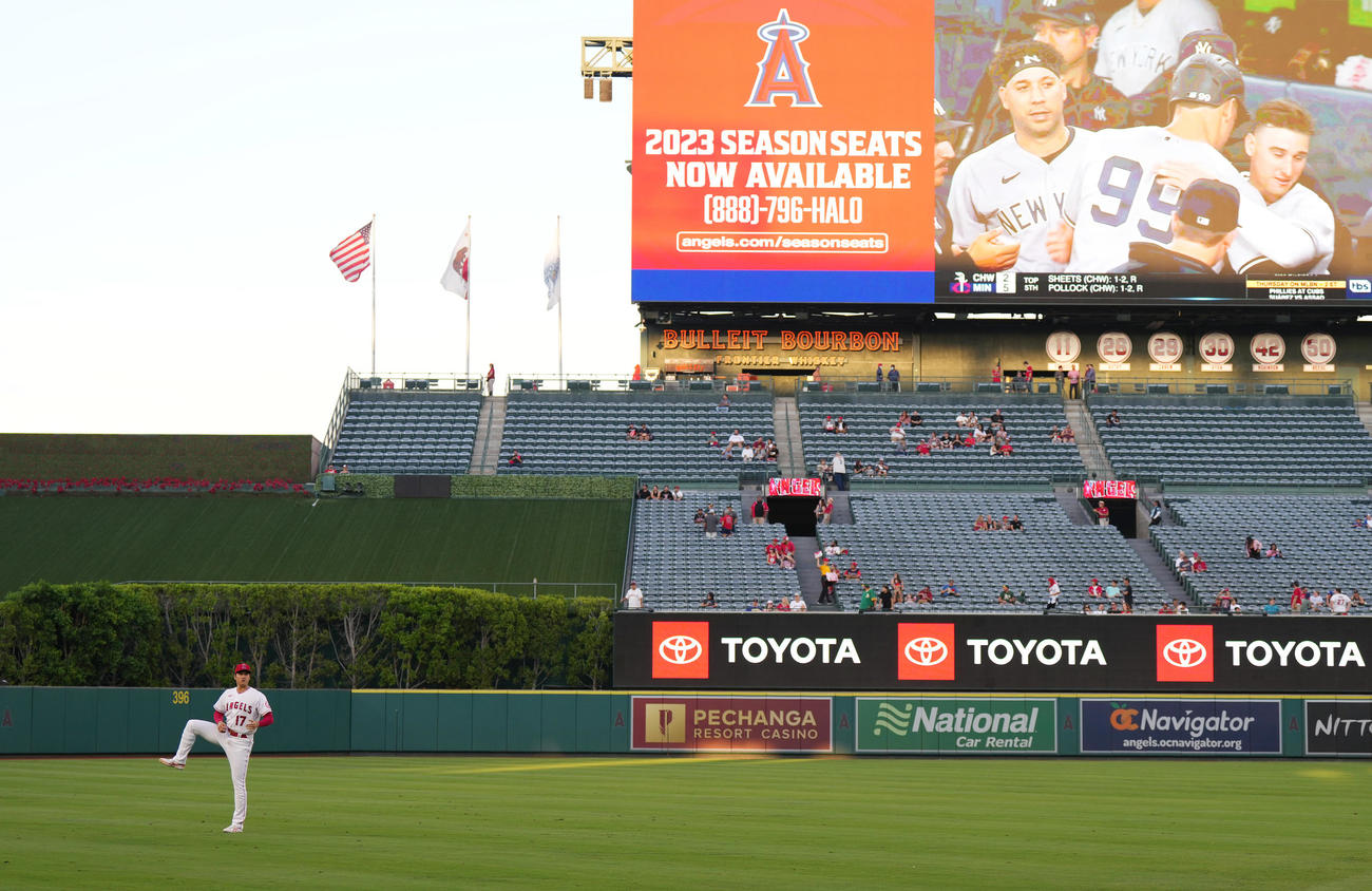 エンゼルス対アスレチックス　試合前、電光掲示板に映し出されるヤンキース・ジャッジの61号本塁打の映像を背にアップをする大谷（左）（撮影・菅敏）