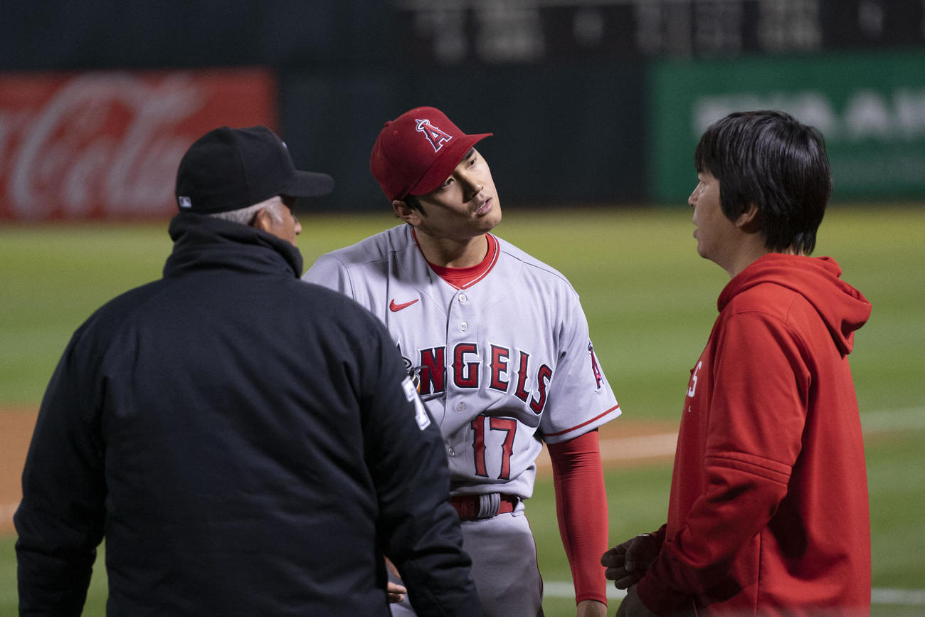 水原通訳（右）を挟んで審判と話しながら首をひねる大谷翔平（USA TODAY）