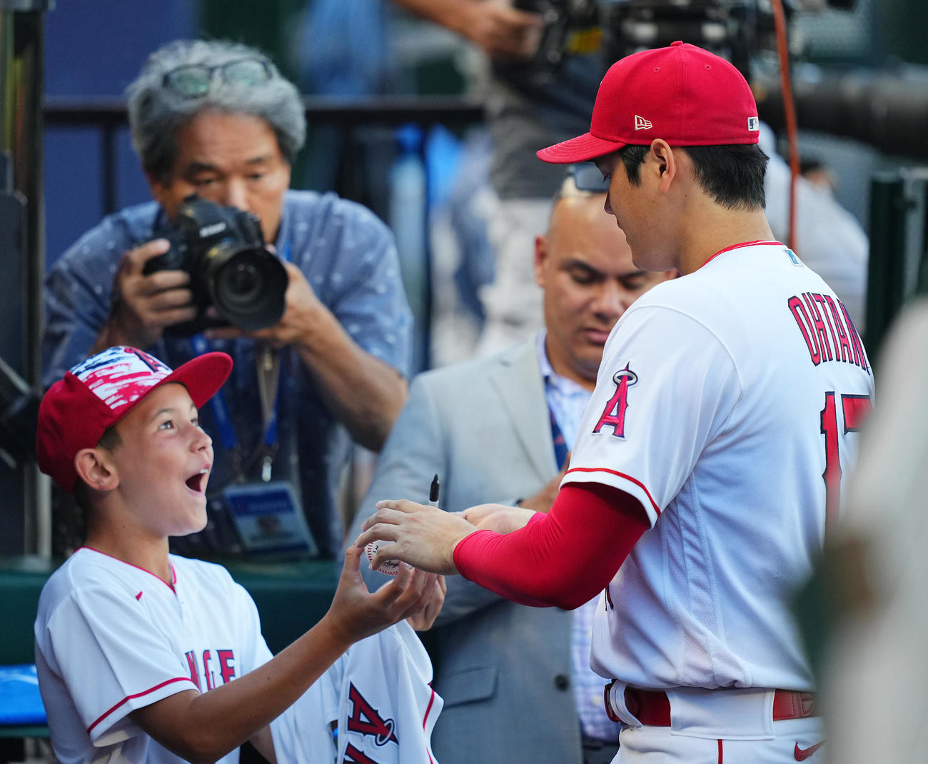 エンゼルス対マリナーズ　試合前、ウオーミングアップを終えたエンゼルス大谷（右）はベンチで少年のボールにサインする（撮影・垰建太）