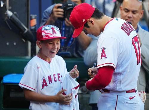 エンゼルス対マリナーズ　試合前、ウオーミングアップを終えたエンゼルス大谷（右）はベンチで少年のボールにサインする（撮影・垰建太）