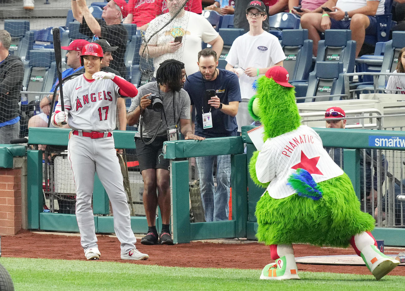 フィリーズ対エンゼルス　試合前、似顔絵を描く球団マスコットのファナティック（右）を前に笑顔を見せる大谷（撮影・菅敏）