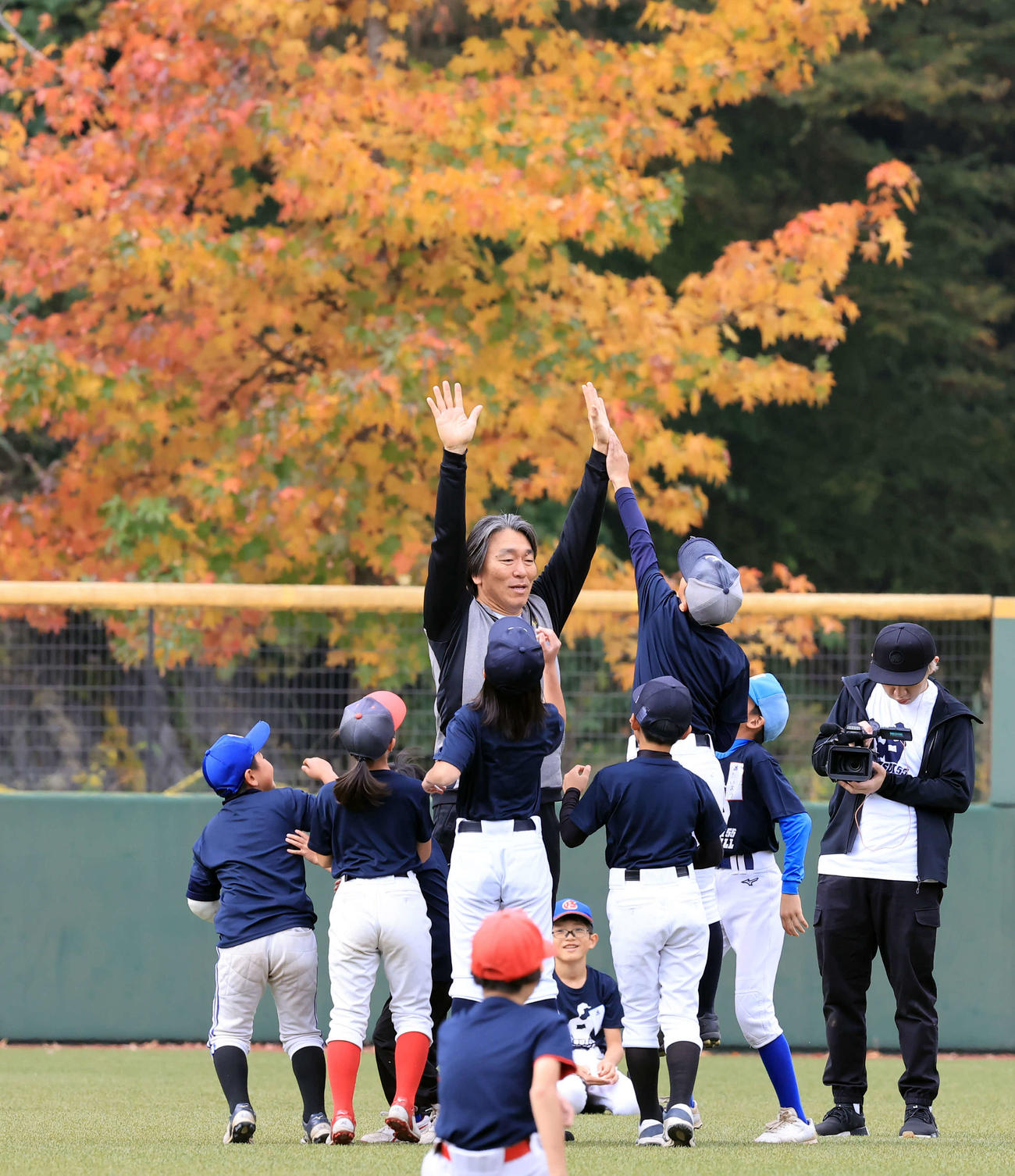 「松井秀喜野球教室」で、紅葉を背に子どもたちとハイタッチする松井秀喜氏（撮影・浅見桂子）