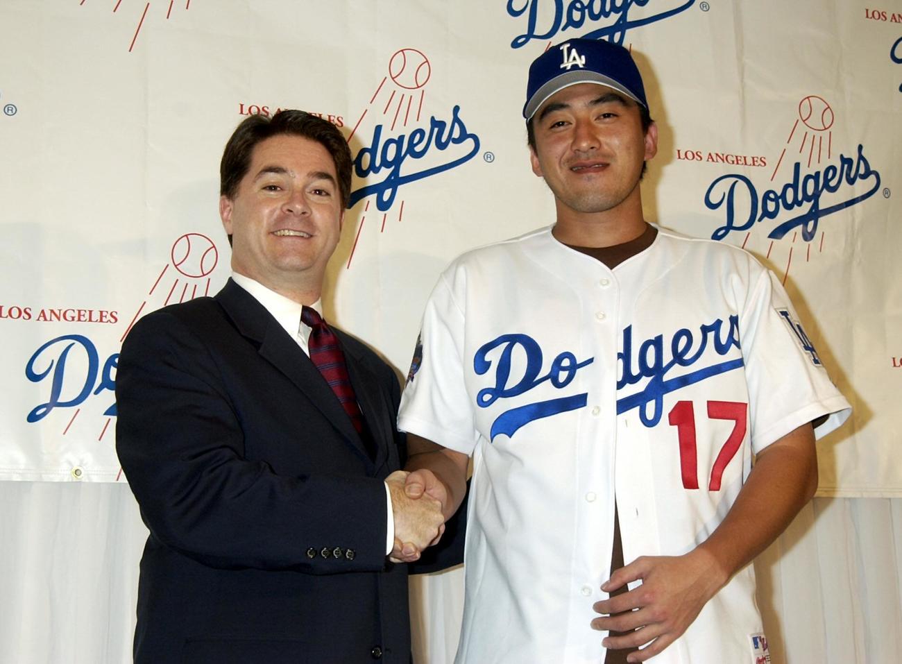 石井一久（右）はユニホームを着てドジャースのダニエル・エバンスGMと握手を交わす（02年2月11日）
