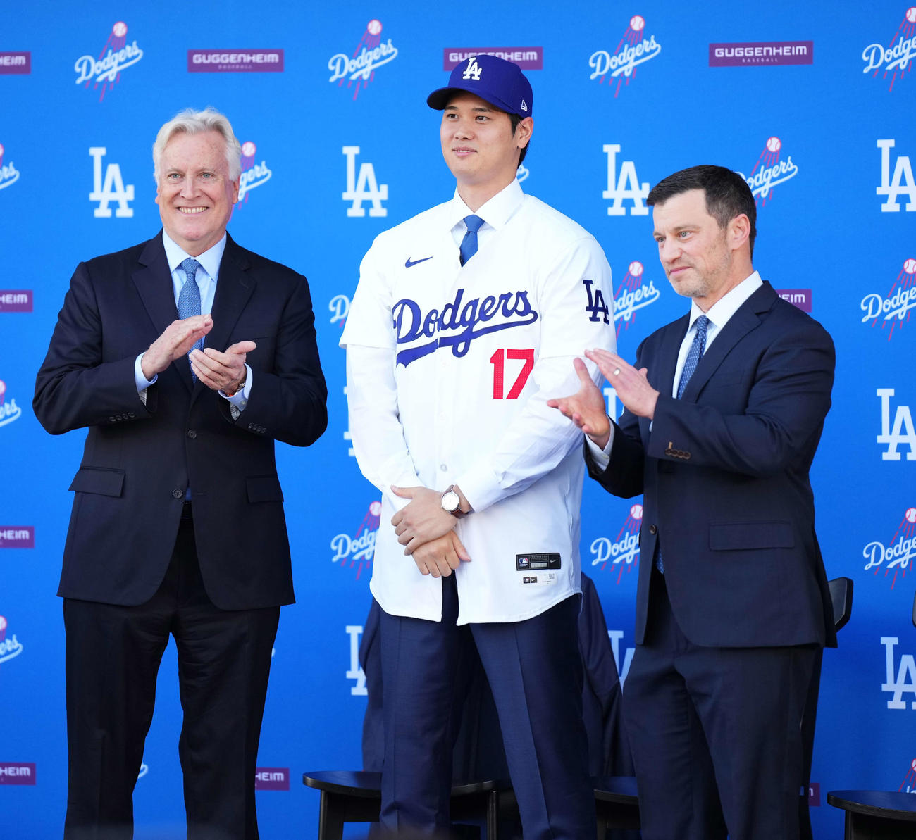 14日、入団会見でドジャースのユニホームに袖を通し笑顔を見せる大谷。左は球団オーナーのウォルター氏、右はフリードマン編成本部長