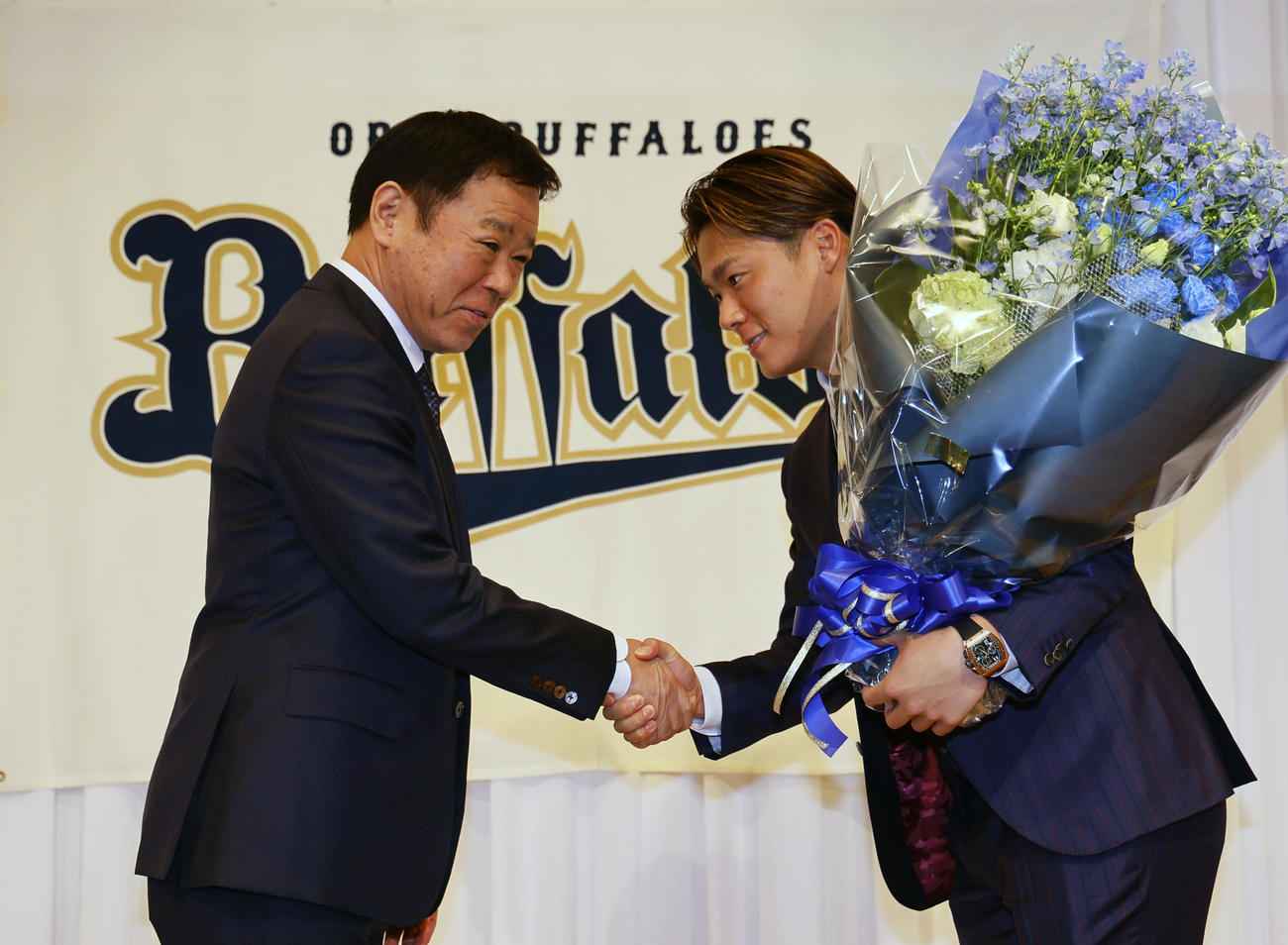 記者会見を終え、オリックス福良GM（左）から花束を贈られる山本（撮影・藤尾明華）