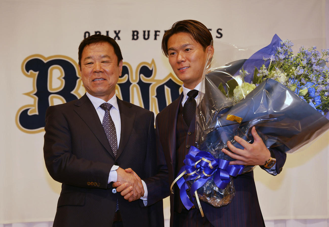 記者会見を終え、オリックス福良GM（左）から花束を贈られ握手を交わす米大リーグドジャースに入団が決まった山本（撮影・藤尾明華）