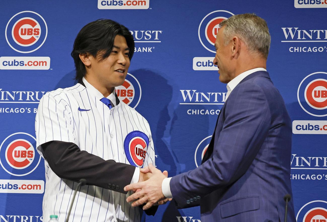 米大リーグ、カブスの入団記者会見で、ホイヤー編成本部長（右）と握手する今永昇太投手（共同）