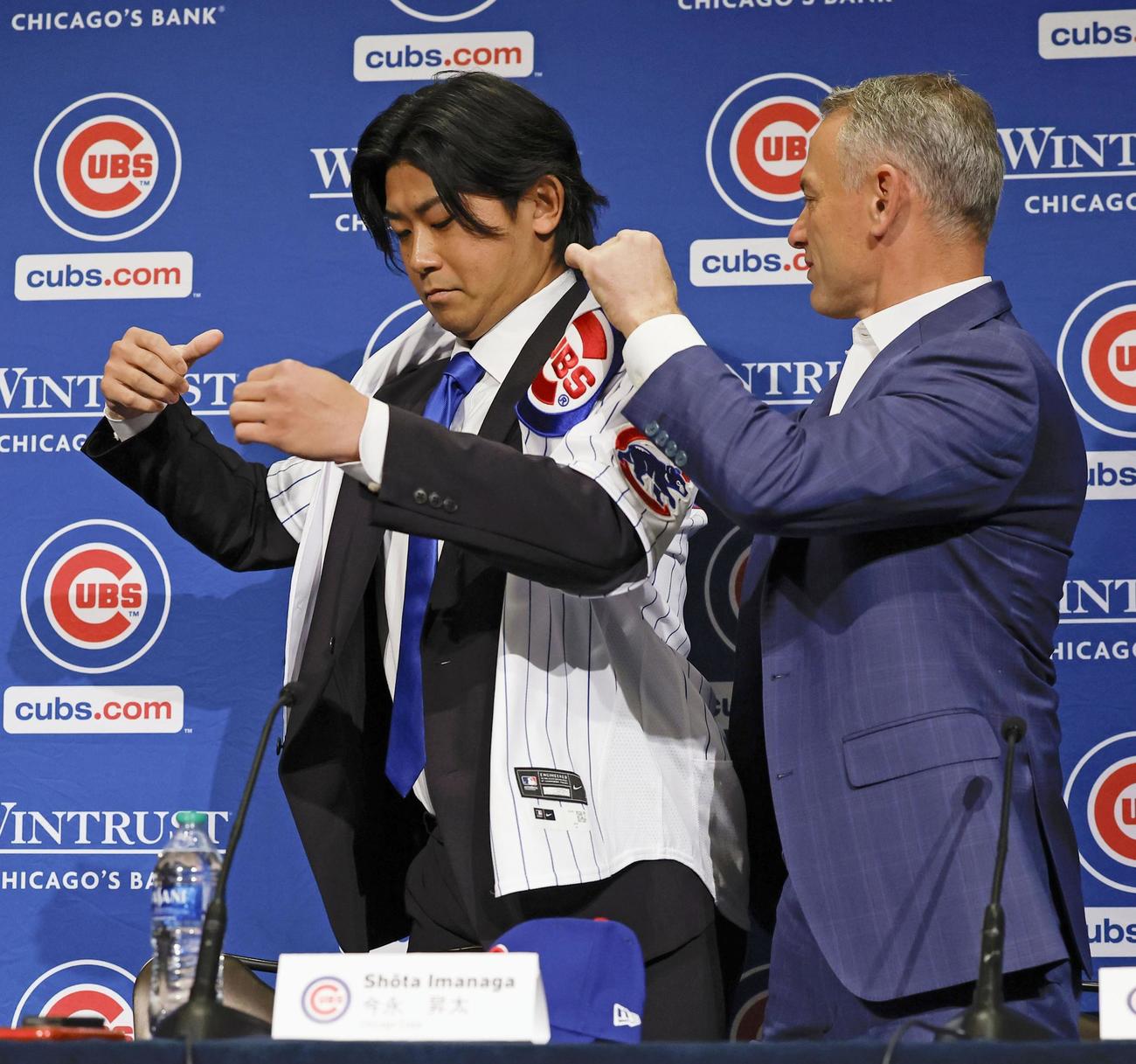 米大リーグ、カブスの入団記者会見で、ホイヤー編成本部長（右）にユニホームを着せてもらう今永昇太投手（共同）