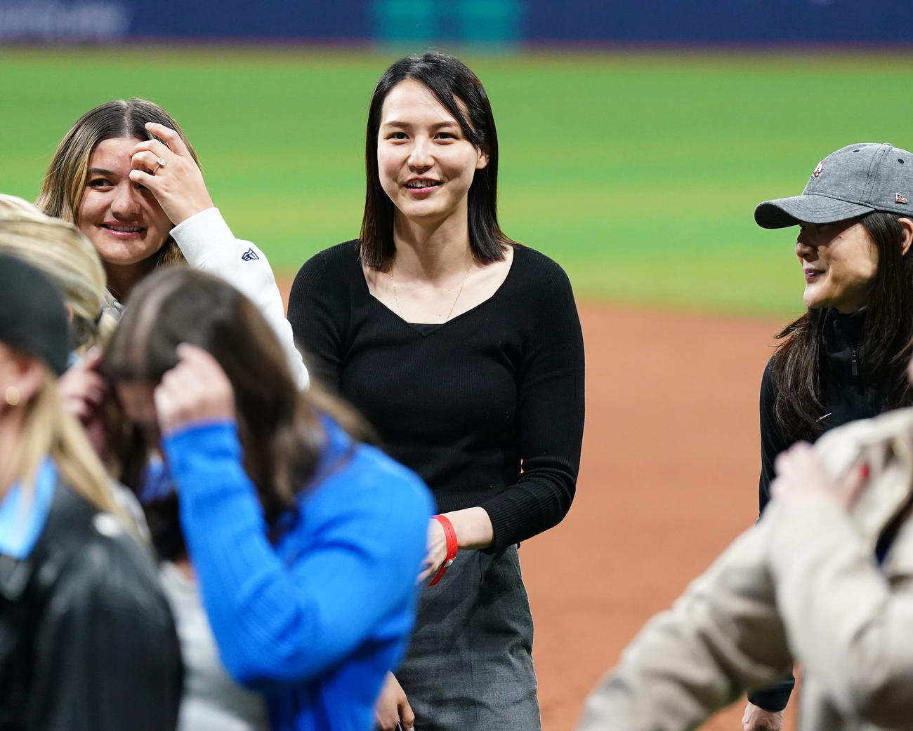 ドジャース対パドレス　試合後にフィールドで関係者と笑顔で話す真美子夫人（中央）（撮影・菅敏）