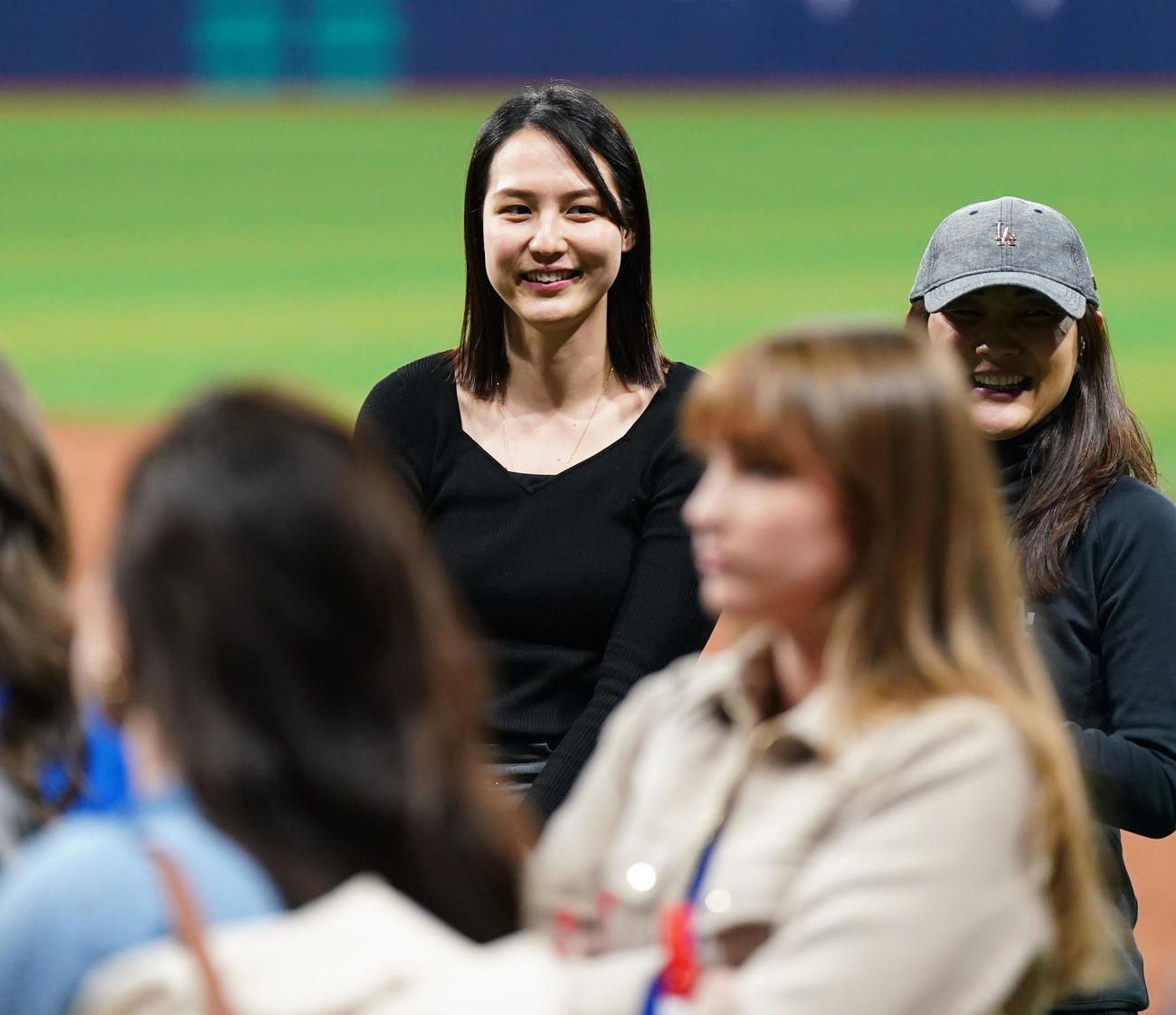 ドジャース対パドレス　試合後にフィールドで関係者と笑顔で話す真美子夫人（左）（撮影・菅敏）
