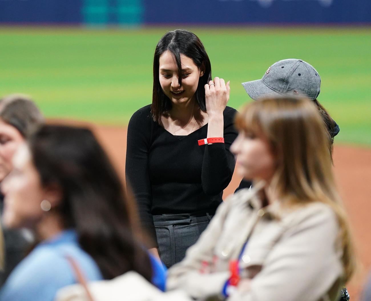 ドジャース対パドレス　試合後にフィールドで関係者と笑顔で話す真美子夫人（中央）（撮影・菅敏）