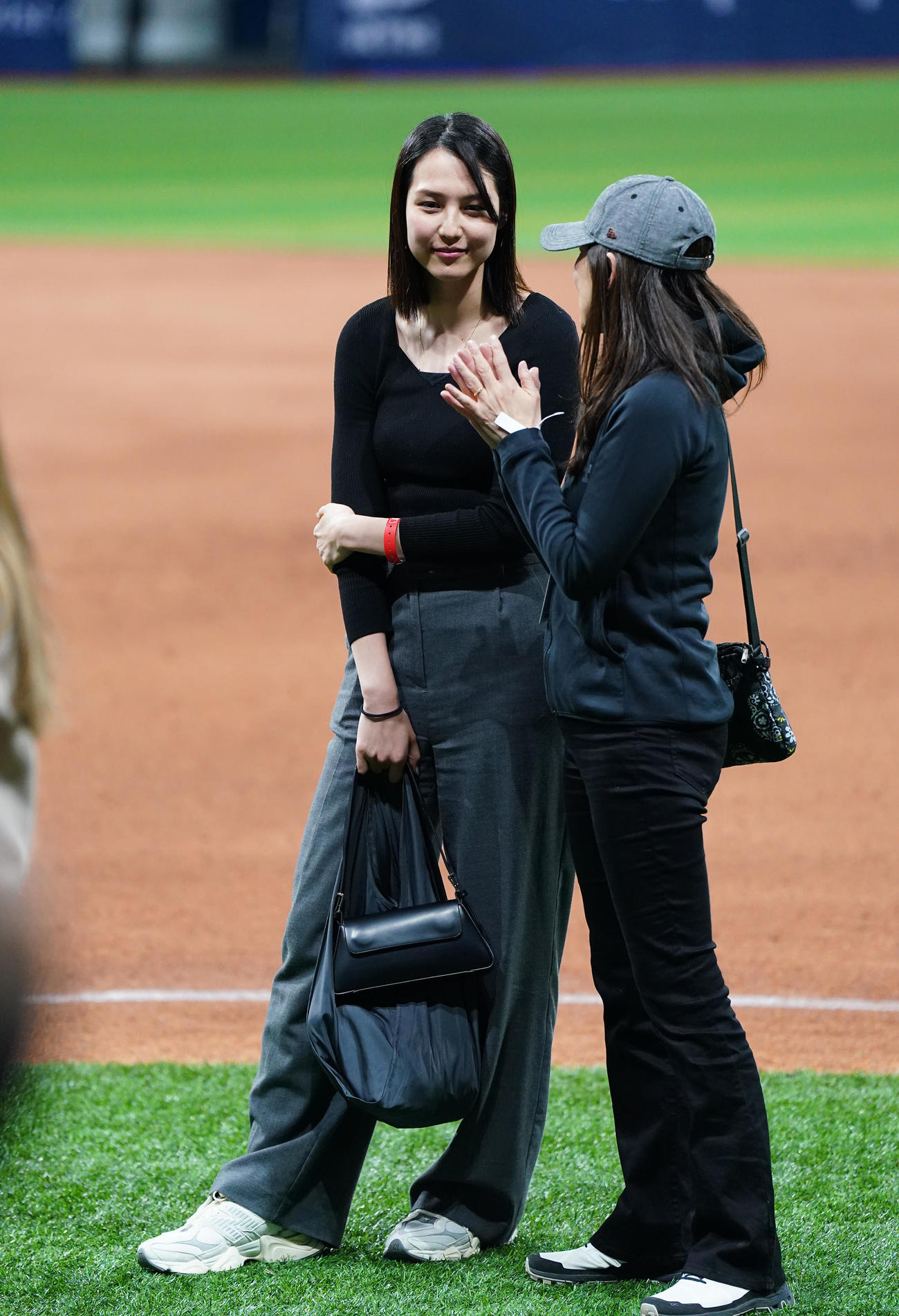 ドジャース対パドレス　試合後にフィールドで関係者と笑顔で話す真美子夫人（左）（撮影・菅敏）