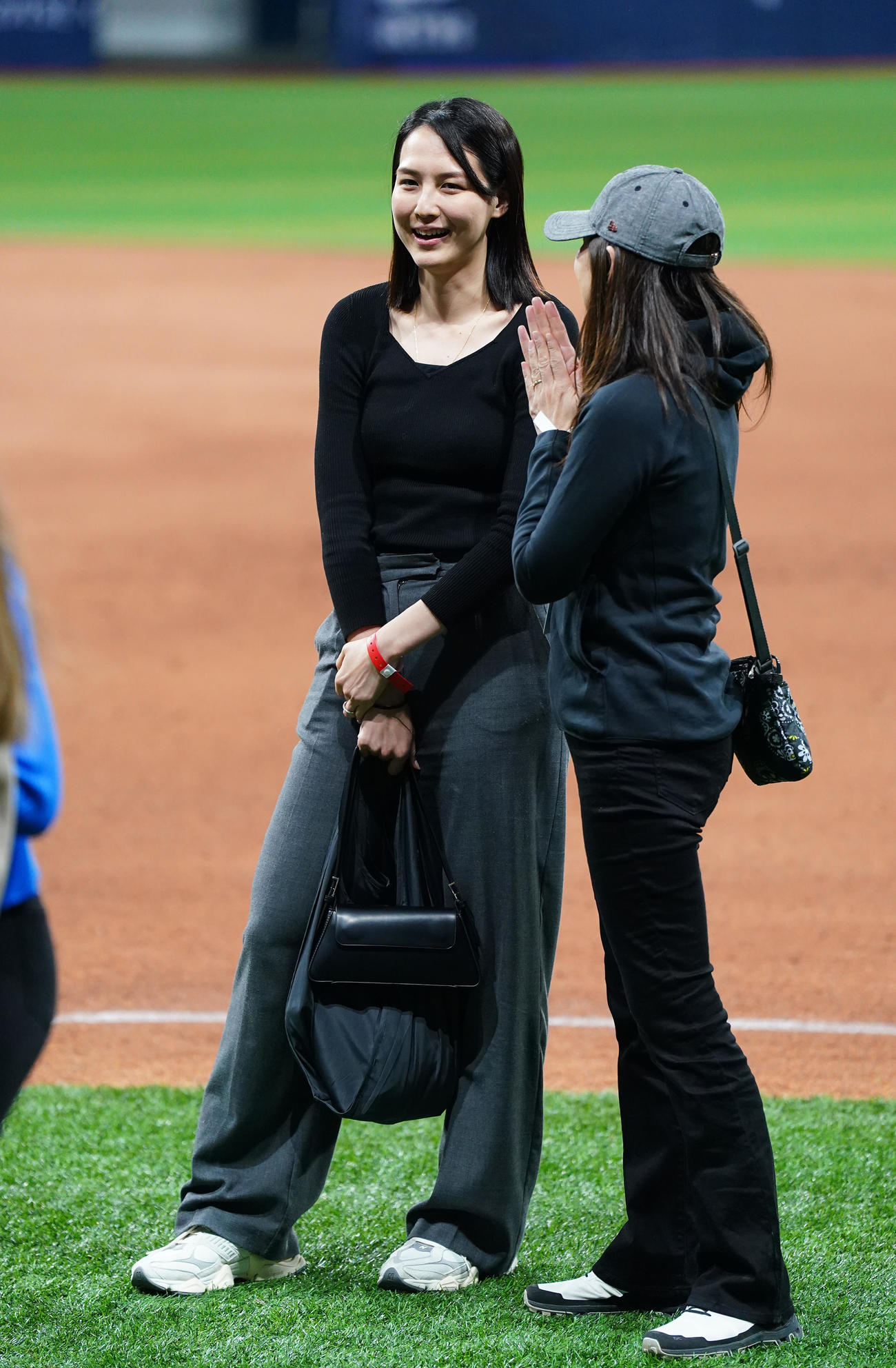 ドジャース対パドレス　試合後にフィールドで関係者と笑顔で話す真美子夫人（左）（撮影・菅敏）